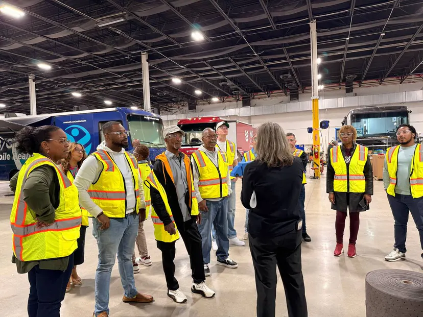 A group in high-visibility vests on a tour of the mobile clinic shop floor